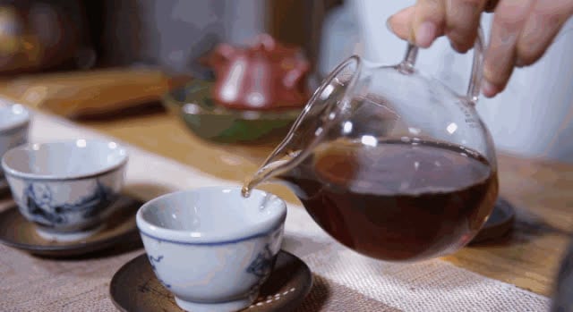 Green tea leaves moving in a clear glass infusion